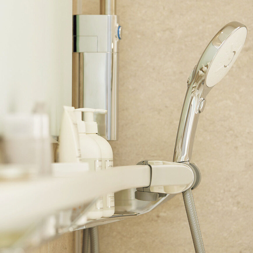 シャワーと、棚に置かれた白いアメニティグッズ